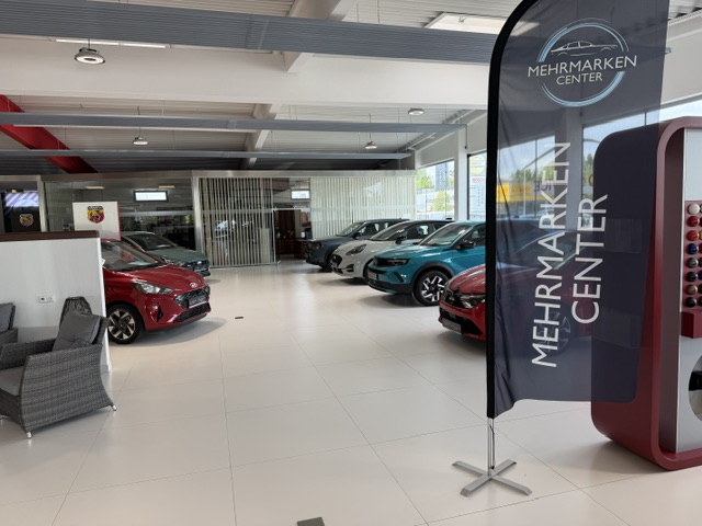 Das Autohaus von innen. Eine Flagge mit dem Mehrmarken-Center Logo ist zu sehen