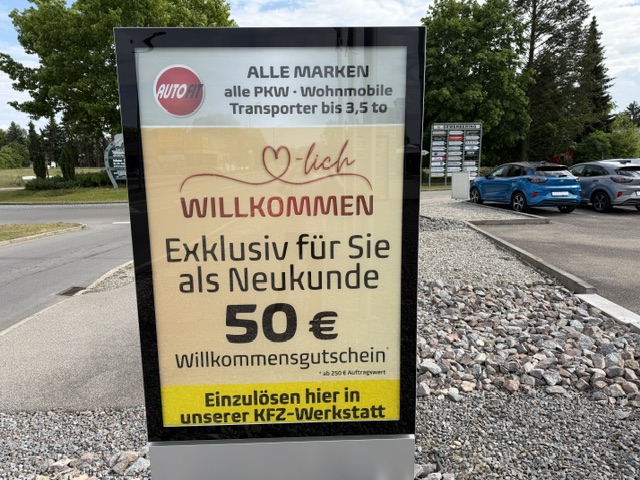Ein Schild außerhalb des Autohauses, auf dem ein 50 Euro Willkommensgutschein beworben wird